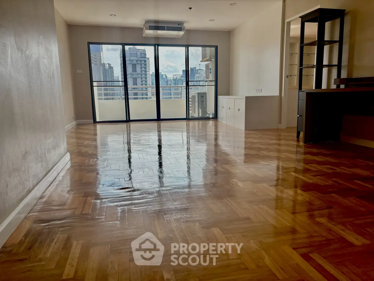 Spacious living room with polished wooden floors and city view balcony.