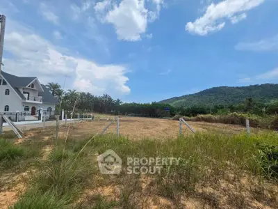 Scenic land plot with mountain views and nearby house, ideal for development.