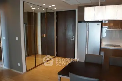 Modern dining area with sleek wooden flooring and mirrored closet doors