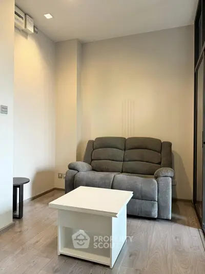 Cozy living room with plush gray sofa and modern white coffee table, perfect for relaxation.
