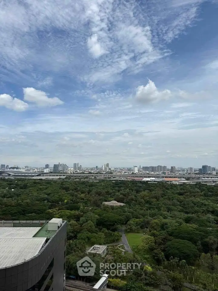 Stunning cityscape view from high-rise building overlooking lush greenery and urban skyline.