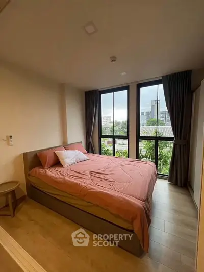 Cozy bedroom with large windows and city view, featuring a comfortable bed and stylish decor.