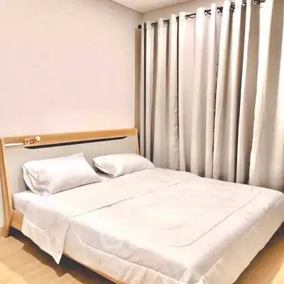 Cozy bedroom with modern design and elegant curtains, perfect for relaxation.