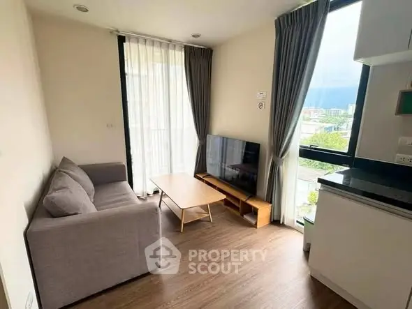 Modern living room with large windows and mountain view, featuring a cozy sofa and sleek TV setup.