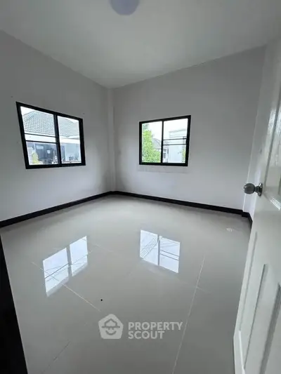 Spacious empty room with large windows and glossy tiled floor, perfect for customization.