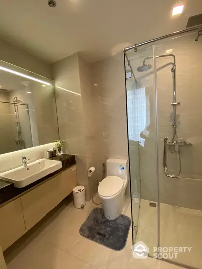 Modern bathroom with glass shower and sleek vanity in luxury apartment