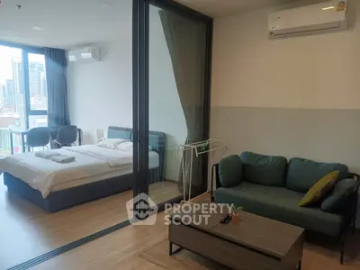 Modern studio apartment with glass partition, cozy living area, and city view balcony.