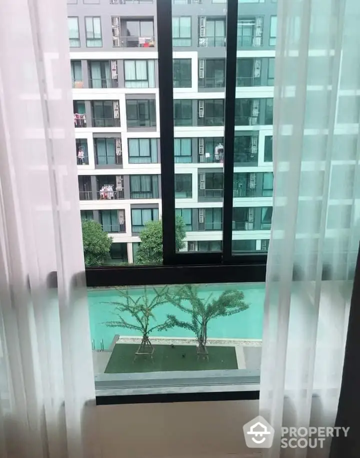 Modern apartment view with pool and greenery from window