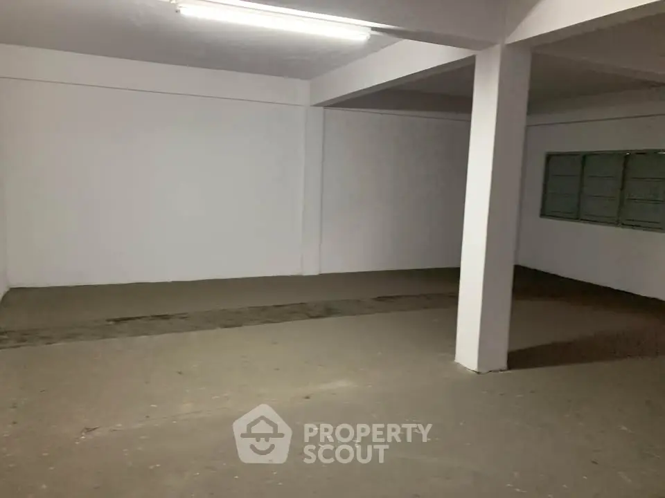 Spacious empty room with concrete floor and white walls, ideal for storage or renovation.