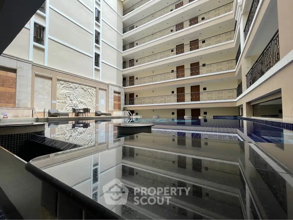 Luxurious indoor pool area in modern apartment building with elegant balconies and artistic wall decor.