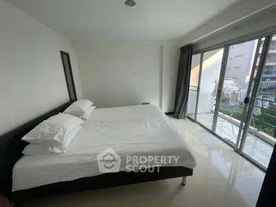 Spacious bedroom with large windows and balcony access in modern apartment