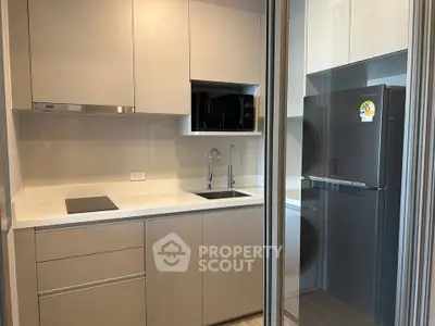 Modern compact kitchen with sleek cabinetry and built-in appliances in a stylish apartment.