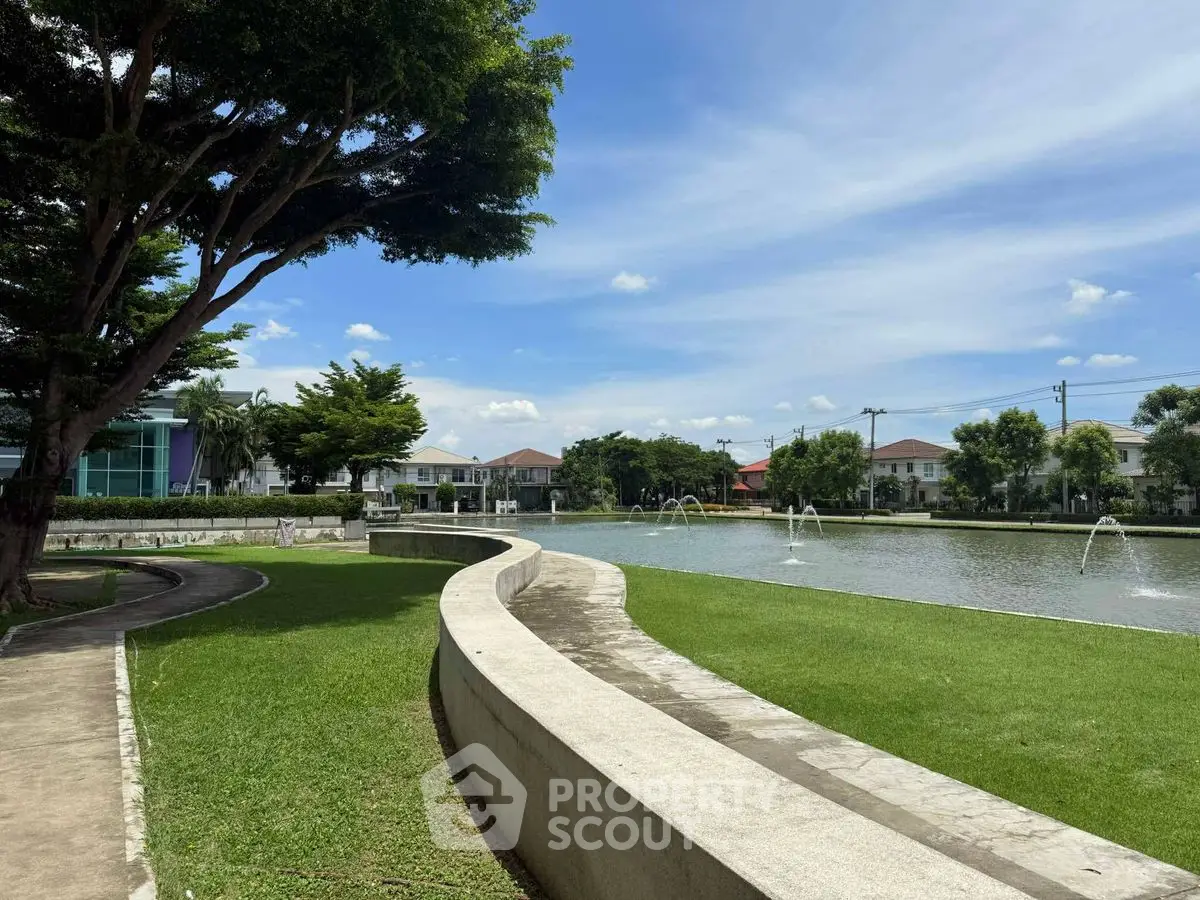 Scenic view of a serene residential area with a pond and lush greenery, perfect for tranquil living.