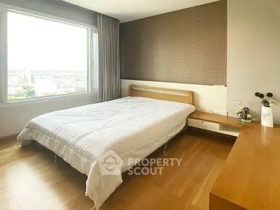 Spacious bedroom with large window offering stunning city views, featuring modern wooden furniture and elegant decor.
