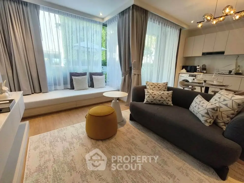 Modern living room with stylish decor and open kitchen layout, featuring large windows and cozy seating area.
