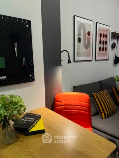 Modern living room with stylish decor, featuring a cozy sofa, vibrant chair, and contemporary wall art.