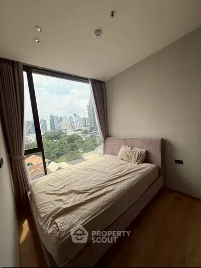 Cozy bedroom with city view, featuring a large window and modern decor.