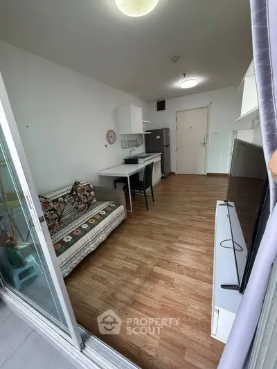 Cozy studio apartment with open layout, featuring a compact kitchen and stylish wooden flooring.