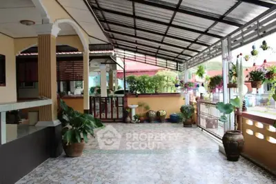 Charming covered patio with tiled flooring and lush potted plants in a cozy residential setting.