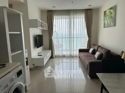 Modern living room with ocean view, featuring a cozy sofa, wall-mounted TV, and washing machine.