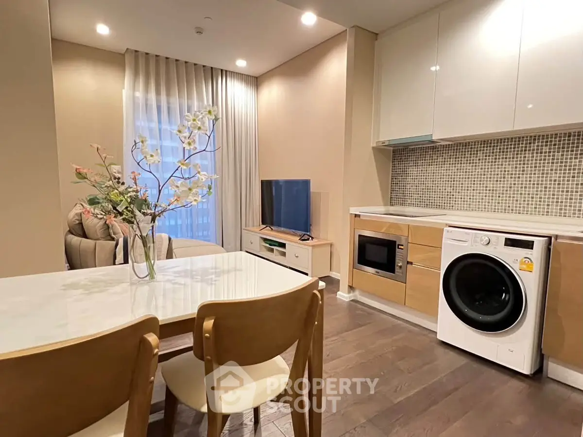 Modern living room with integrated kitchen featuring washing machine and microwave