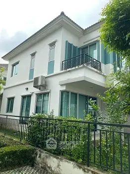Modern two-story house with balcony and lush greenery