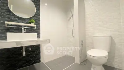 Modern bathroom with sleek black and white tiles, featuring a stylish sink and shower area.