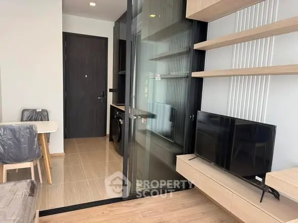 Modern living room with sleek TV setup and open kitchen layout in stylish apartment.