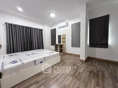 Spacious modern bedroom with wooden flooring and stylish curtains