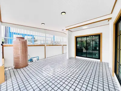 Spacious covered balcony with modern tile flooring and large windows.