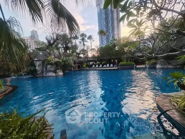 Luxurious residential pool with lush greenery and city skyline view.