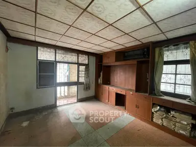 Spacious vintage living room with built-in wooden cabinets and large windows for natural light.