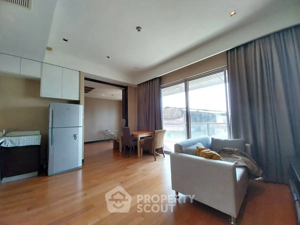 Spacious living room with modern furniture and large windows leading to a balcony.