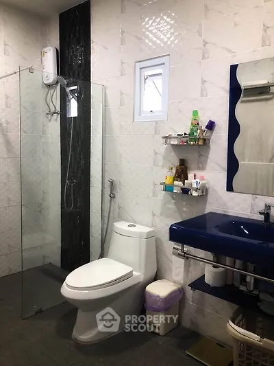 Modern bathroom with glass shower and blue sink in stylish home.
