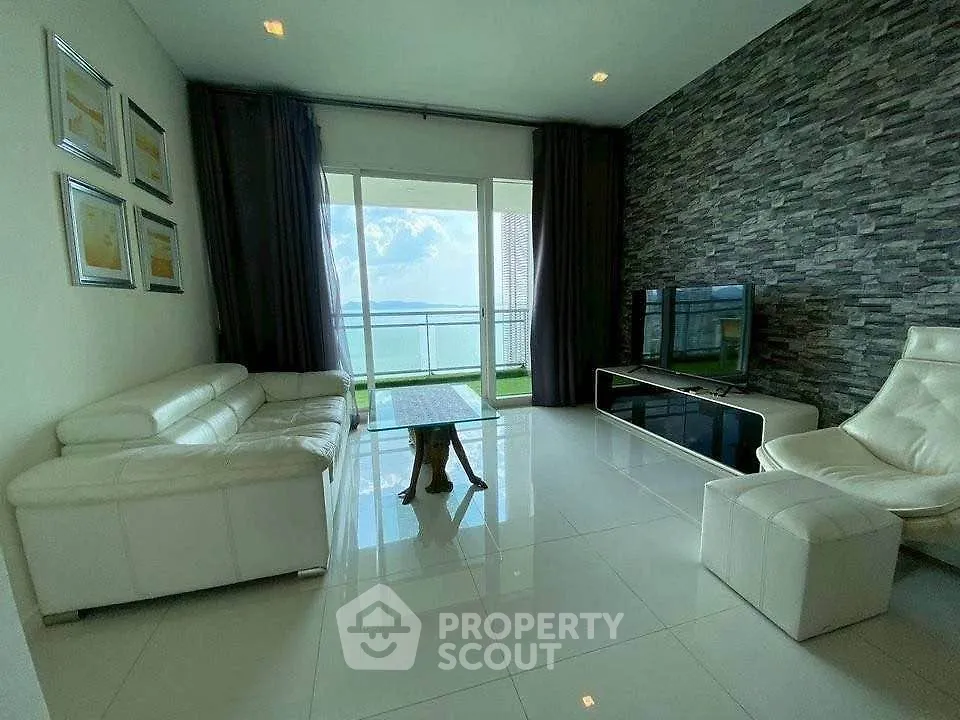 Luxurious living room with modern decor and stunning ocean view from large windows.