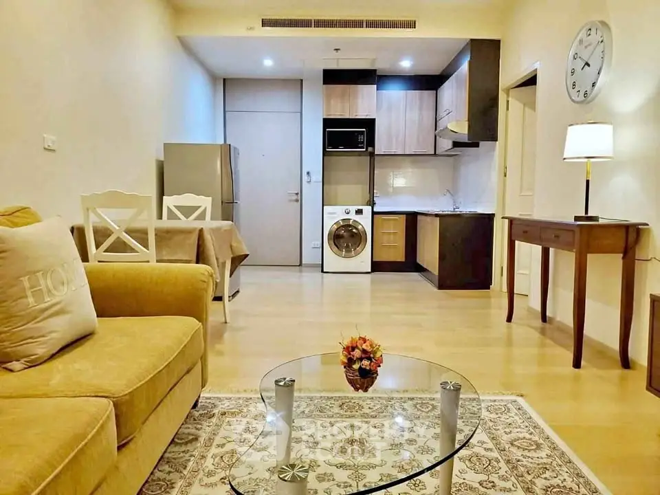 Cozy living room with modern kitchen, featuring washing machine and fridge, perfect for urban living.