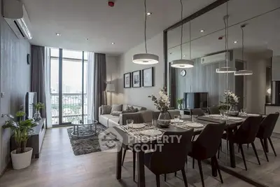 Modern living room with dining area and large mirror, featuring elegant decor and city view.