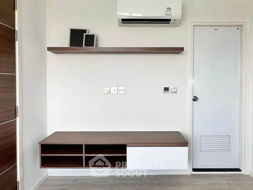 Modern minimalist interior with wall-mounted shelf and air conditioning unit.