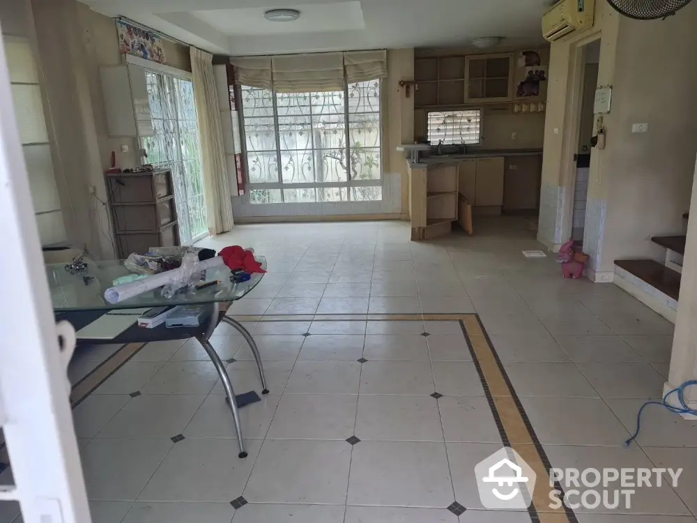 Spacious living room with tiled flooring and large windows in a modern home.