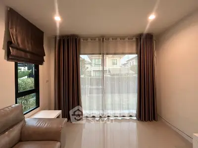 Cozy living room with large window and elegant curtains, perfect for relaxation.