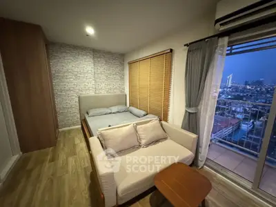 Cozy bedroom with city view, featuring a comfortable bed, sofa, and balcony access.