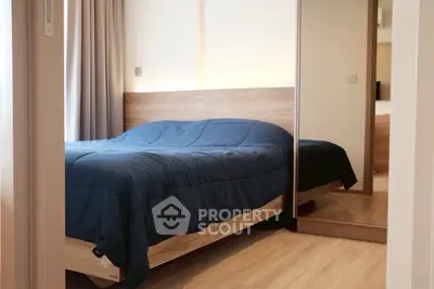 Modern bedroom with wooden flooring and mirrored wardrobe, featuring a cozy bed with blue bedding.