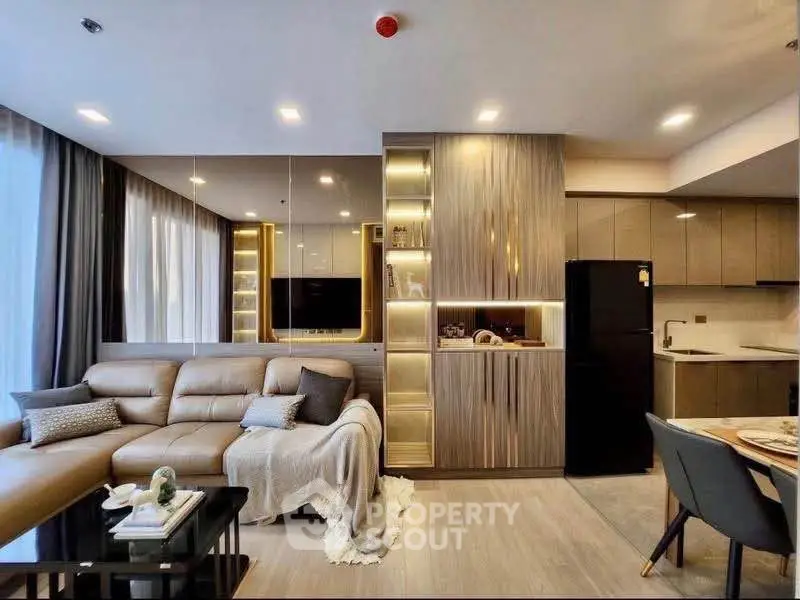 Modern living room with elegant decor and open kitchen layout, featuring sleek furniture and ambient lighting.