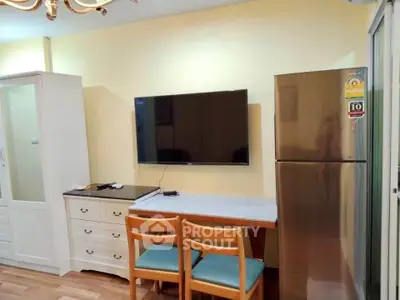 Cozy interior with modern TV setup and stainless steel fridge in a compact living space.