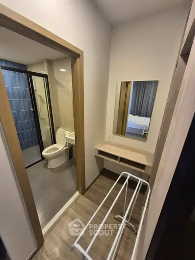 Compact bathroom with modern fixtures and adjacent vanity area in a cozy apartment.