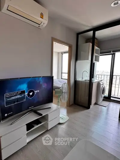 Modern apartment interior with TV, air conditioning, and washing machine near balcony.