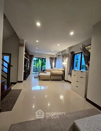 Spacious living room with modern decor and large windows offering natural light and garden view.