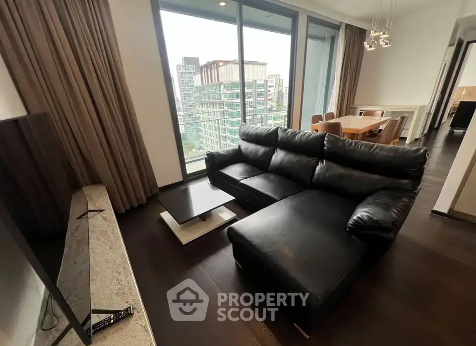 Luxurious living room with city view, featuring modern black leather sofa and elegant dining area.