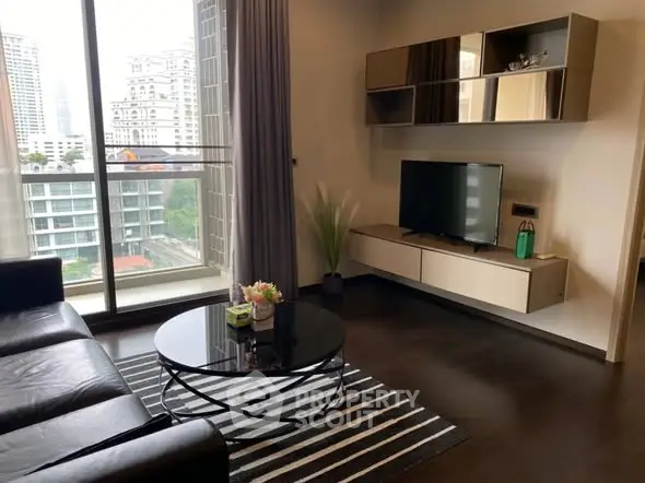 Modern living room with sleek furniture and city view from large window.