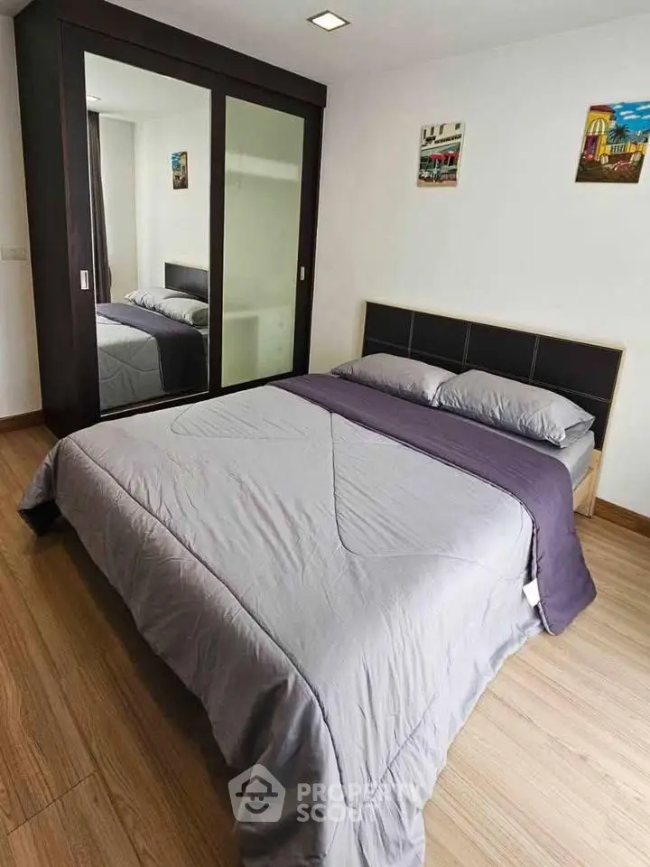 Cozy bedroom with modern decor and mirrored wardrobe in a stylish apartment.